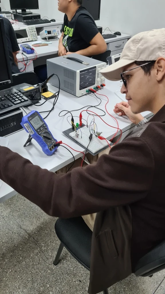 Aluno testando circuito eletrônico com multímetro e protoboard